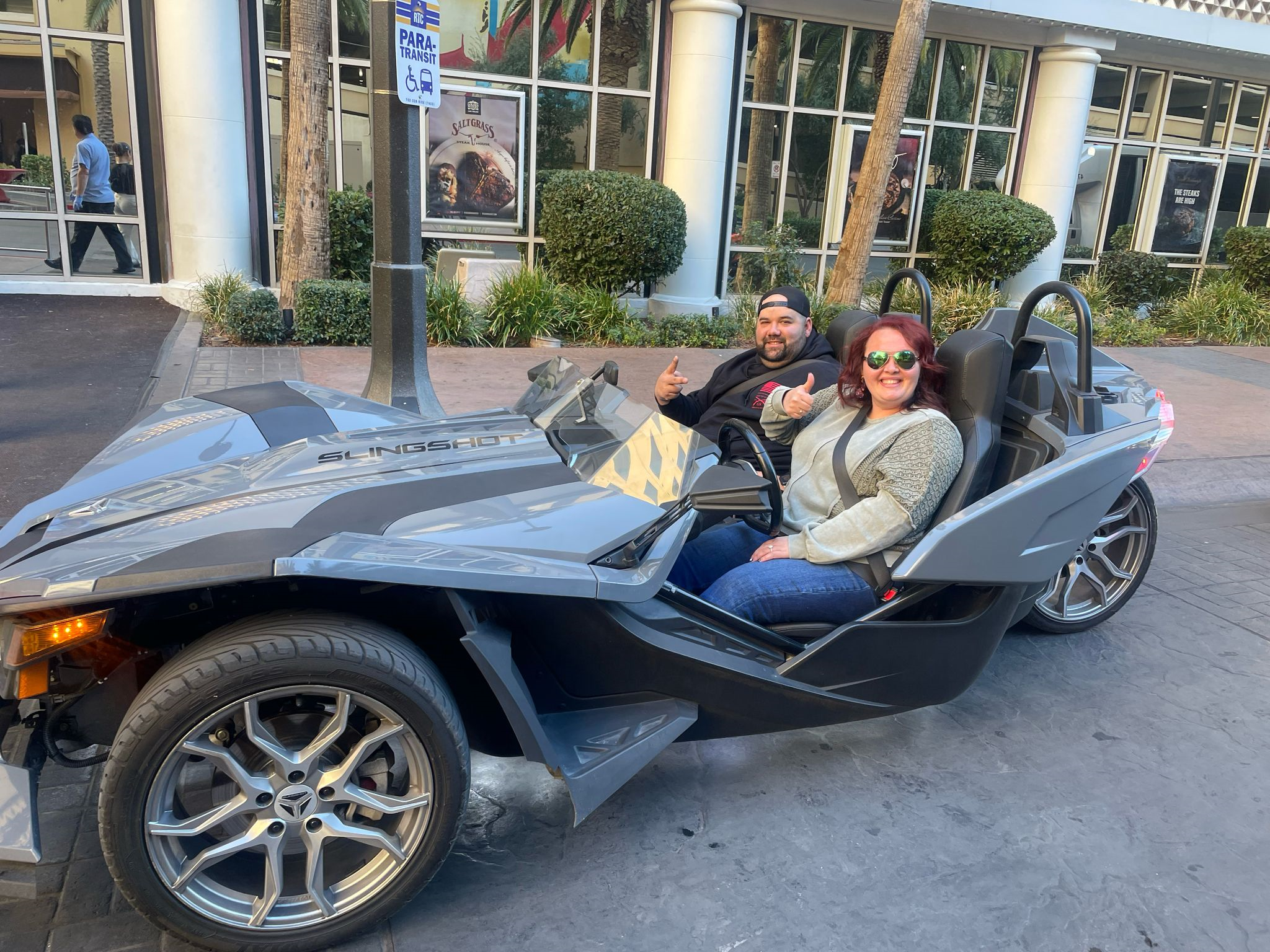 Couple giving thumbs up in grey Slingshot outside Saltgrass Las Vegas