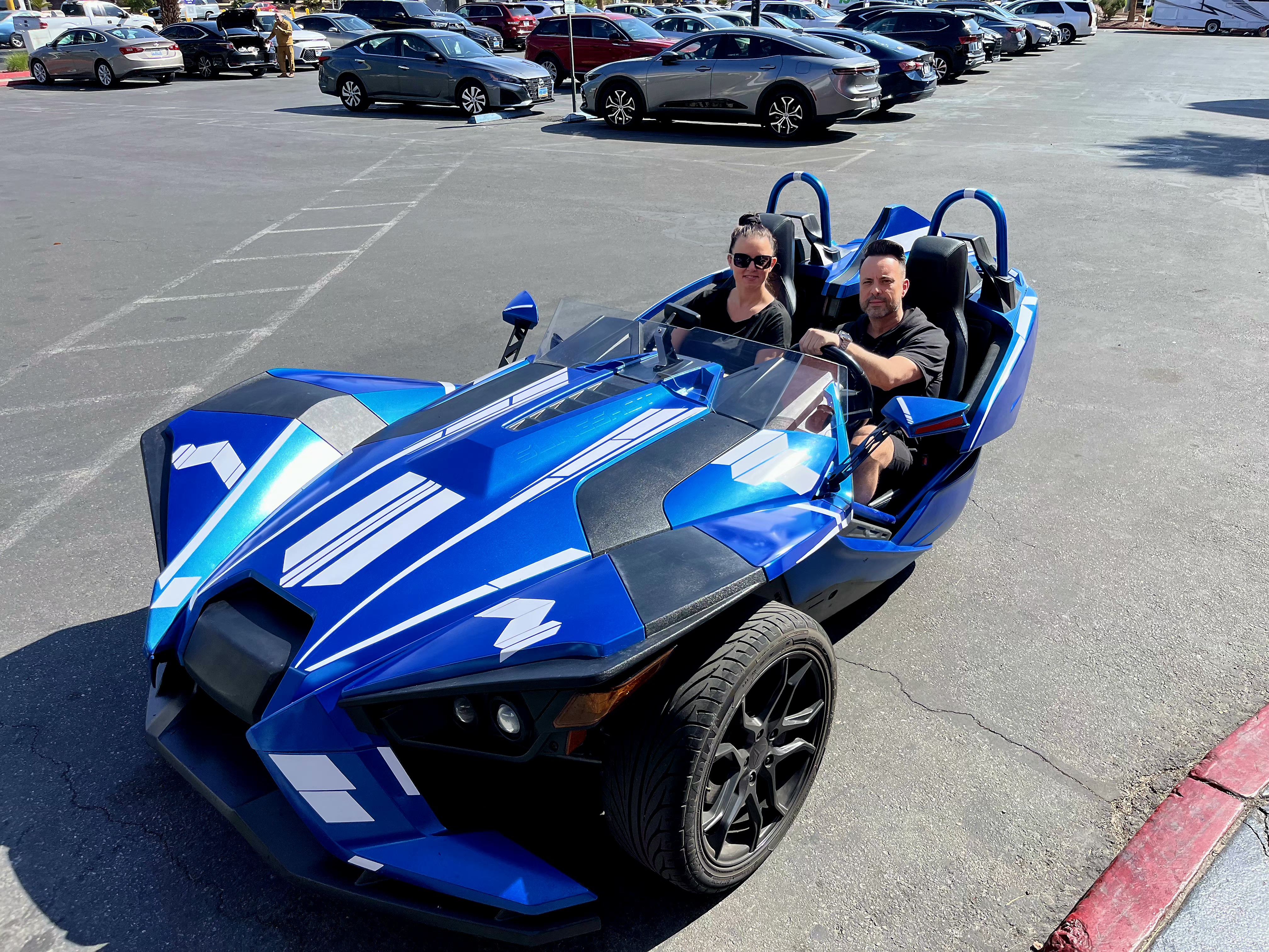 Couple in blue Slingshot in parking lot daytime